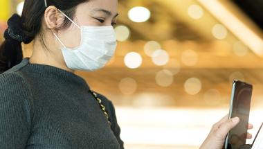 Woman wearing mask using touchless kiosk