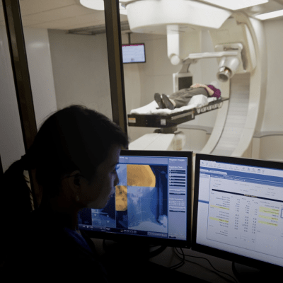 someone getting a radiation scan while medical professional looks at scan on computer